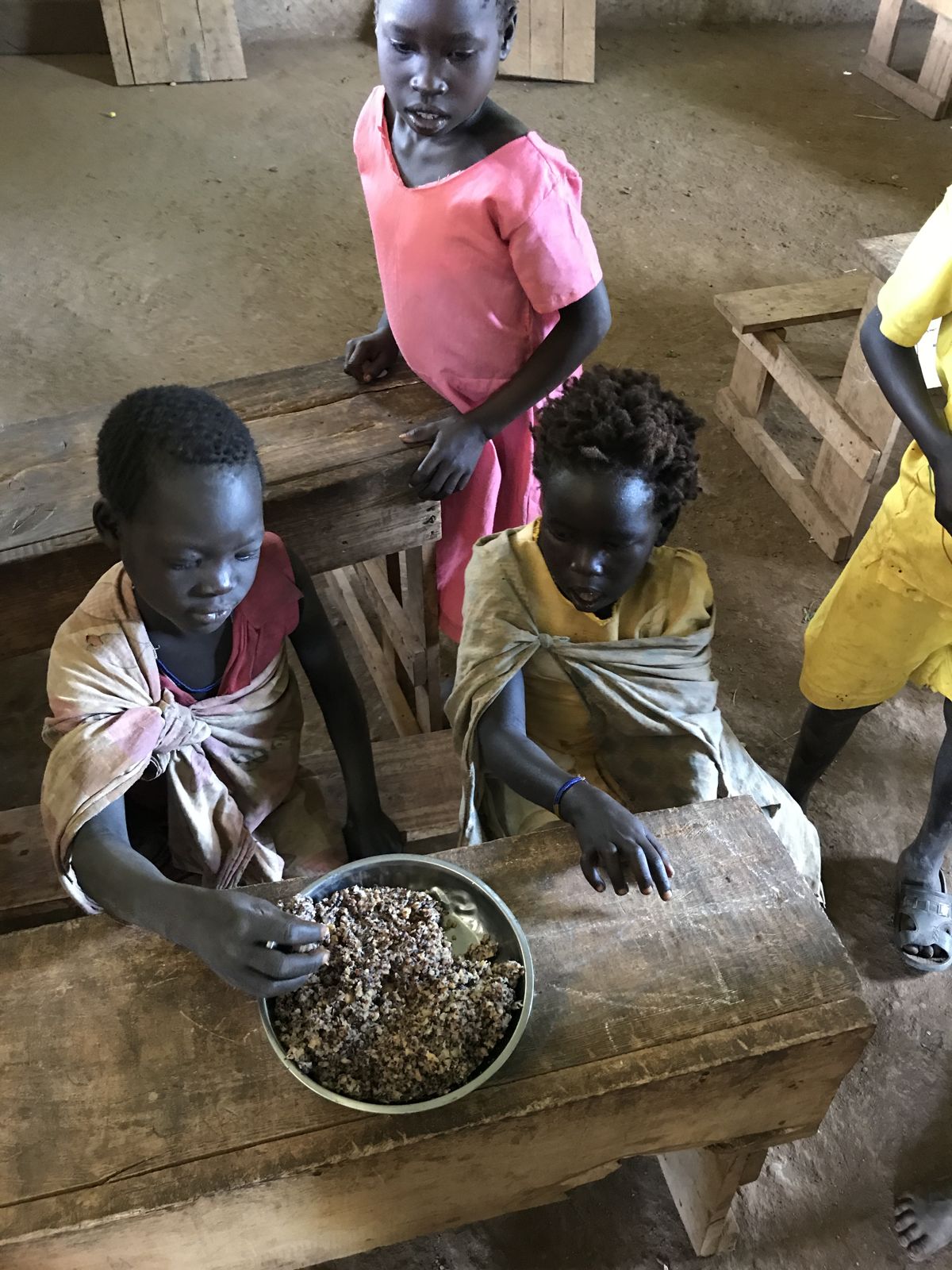 Children share a meal at their school desks in Boma