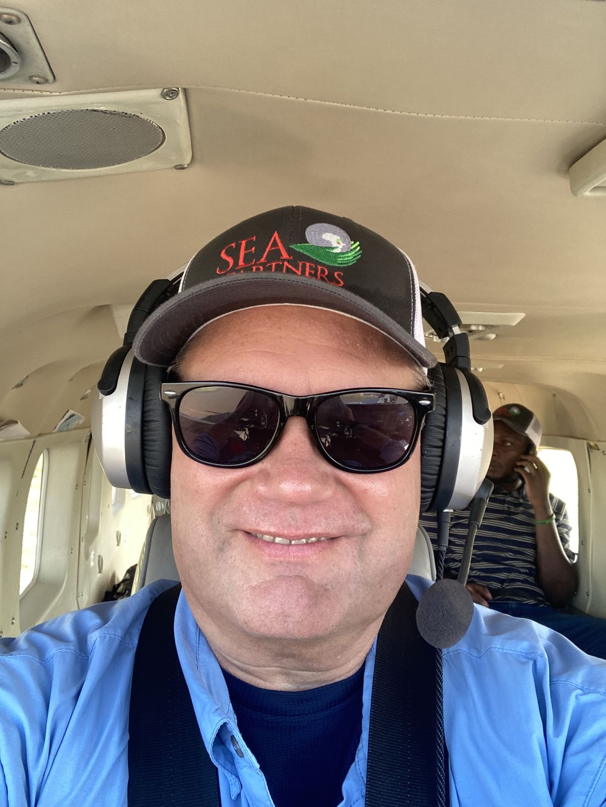 Donnie Brake on the small plane into Boma, wearing a SEA Partners cap