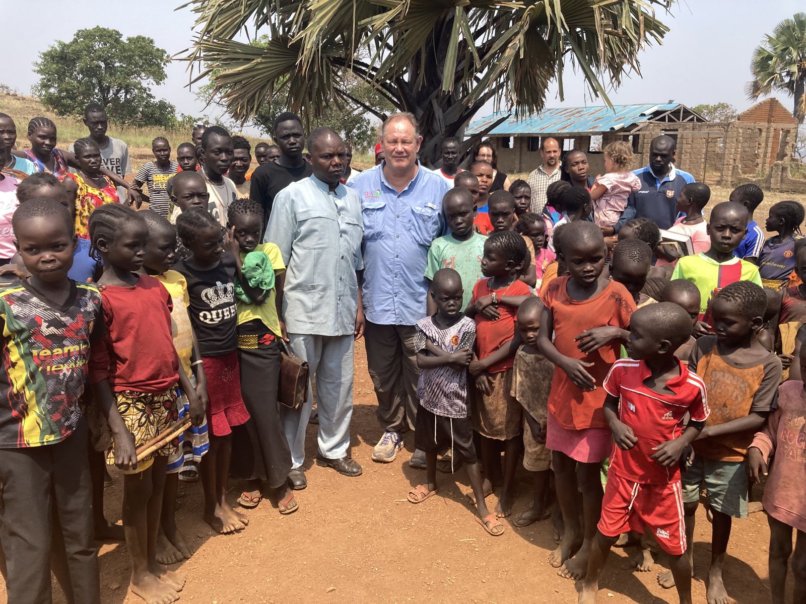 Donnie Brake and a local pastor surrounded by school children in Boma, South Sudan